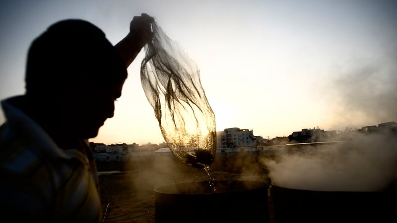 An Israeli man immerses cooking utensils into boiling water to make them kosher for the Jewish festival of Pesah (Passover)