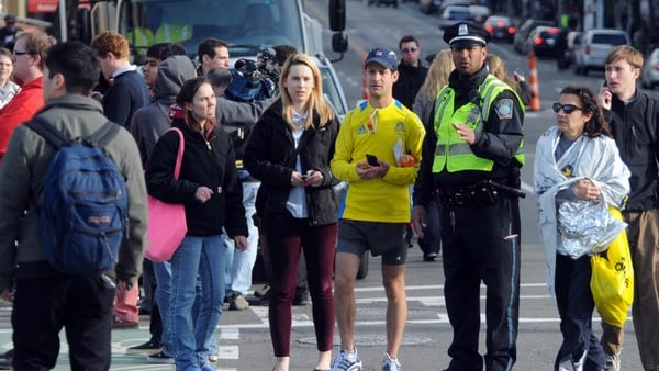 Competitors and spectators are led away from the Boston marathon course