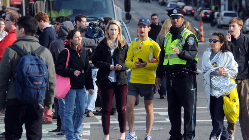 Competitors and spectators are led away from the Boston marathon course