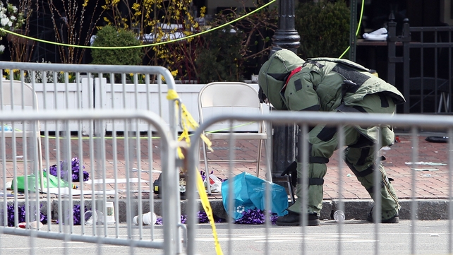 A member of the bomb squad investigates a suspicious item on the road near Kenmore Square in Boston
