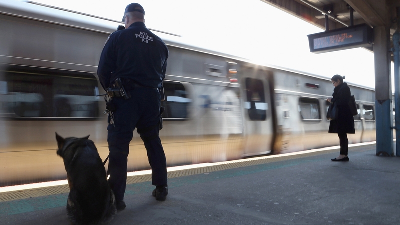 A police officer with his companion keeps guard as a Long Island Rail Road train from New York City arrives at the station in Hicksville, New York