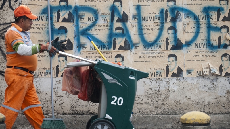 A municipal worker walks past a message painted on a wall in the streets of Caracas reading 'Fraud' as a protest against Venezuelan President-elect Nicolas Maduro