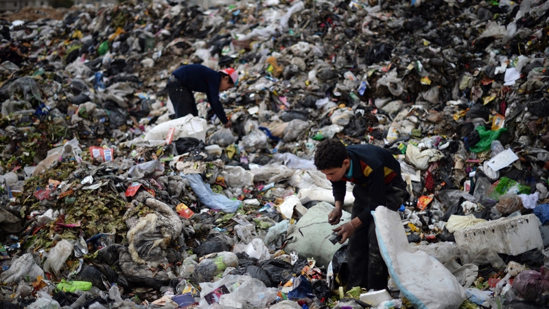 Young Syrian boys collect plastic and metal items in a garbage dump in the northern Syrian city of Aleppo