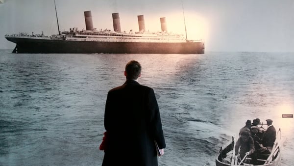 A man stands in front of a photograph taken by Frank Browne of the Titanic departing Queentown on 11 April, 1912