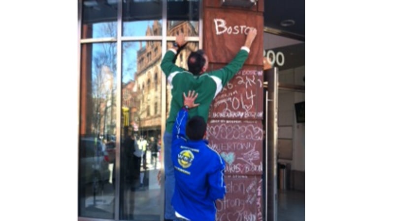 Charles Doherty writes 'Boston you're my home' at a pop up memorial in the city