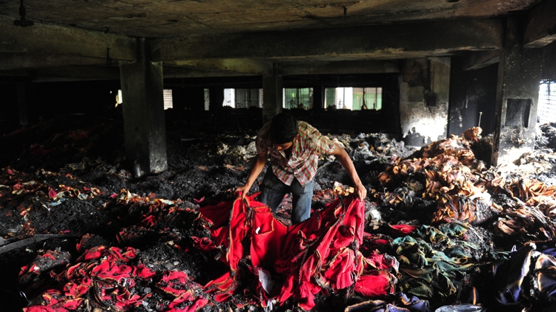 A Bangladeshi garment worker holds up burnt cloth inside the gutted factory in Dhaka
