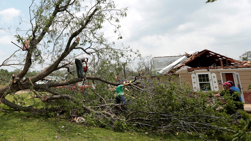 Volunteers chain saw a fallen tree knocked down by a tornado near Shawnee