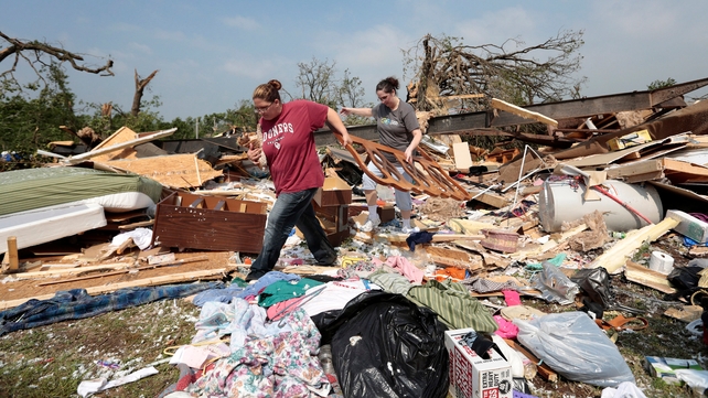 Candice Lopez (L) and Stephanie Davis help clean debris from Thelma Cox's mobile home after it was destroyed by a tornado near Shawnee