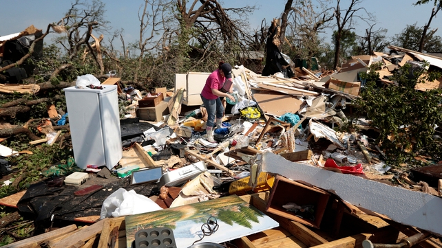 Kasey Clark sorts through debris in her grandmother-in-law's destroyed home