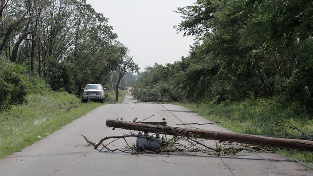 An electrical pole and trees lie across a country road in Oklahoma