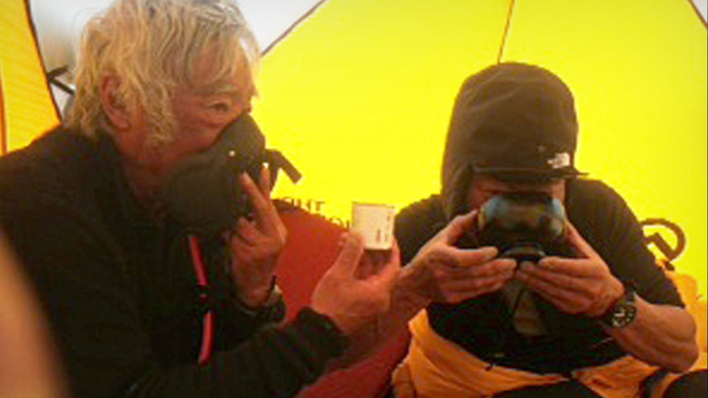 Yuichiro Miura uses an oxygen mask as his son, Gota (R) sips on green tea