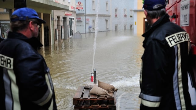 Two firefighters stand next to a pump in the flooded streets of the historic city centre in Passau, Germany.