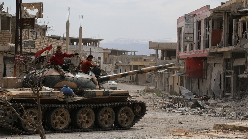 Syrian army soldiers drive a tank through the sacked town of Qusair