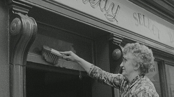 Shopkeeper cleaning front of shop in New Ross, Co. Wexford in preparation for President Kennedy's a…