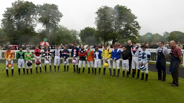 Tom Queally (yellow and red silks) bows his head during a minute's silence for Henry Cecil at Salisbury