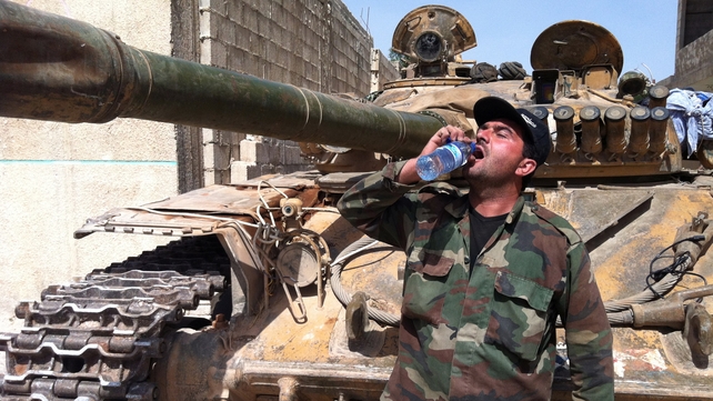 A Syrian army soldier drinking water next to an army tank in the village of Buweida, north of Qusair, as government troops seized the area