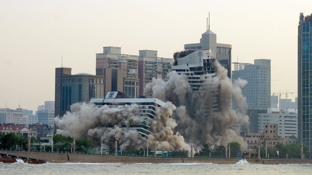 Smoke and dust rise as a 27-year old hotel building is demolished in Qingdao, in east China's Shandong province