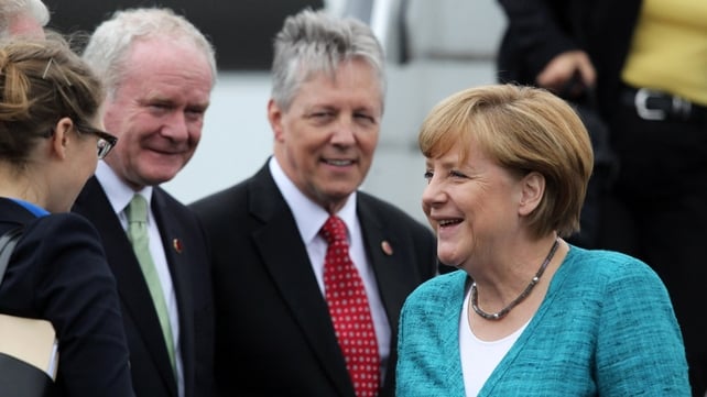German Chancellor Angela Merkel (R) is greeted by Peter Robinson and Martin McGuinness as she arrives at Belfast International Airport