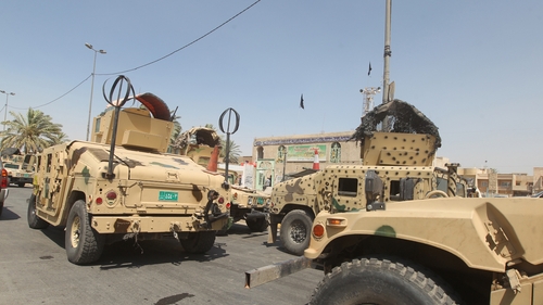 Iraqi military vehicles are stationed in front of the Shia Muslim mosque in Baghdad