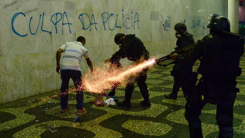 Anti-riot police officers fire tear gas cans during protests in Rio de Janeiro