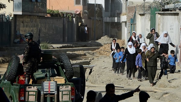 Afghan security forces keep watch as schoolgirls walk near the entrance gate of the presidential palace in the aftermath of attack