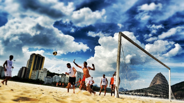 Men play football on Botafogo Beach in Rio de Janeiro