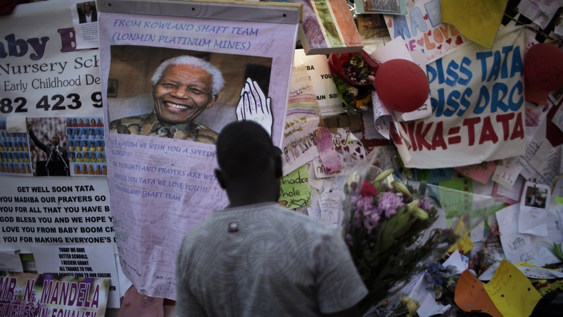 A man holds flowers in front of notes left by well wishers to former president Nelson Mandela