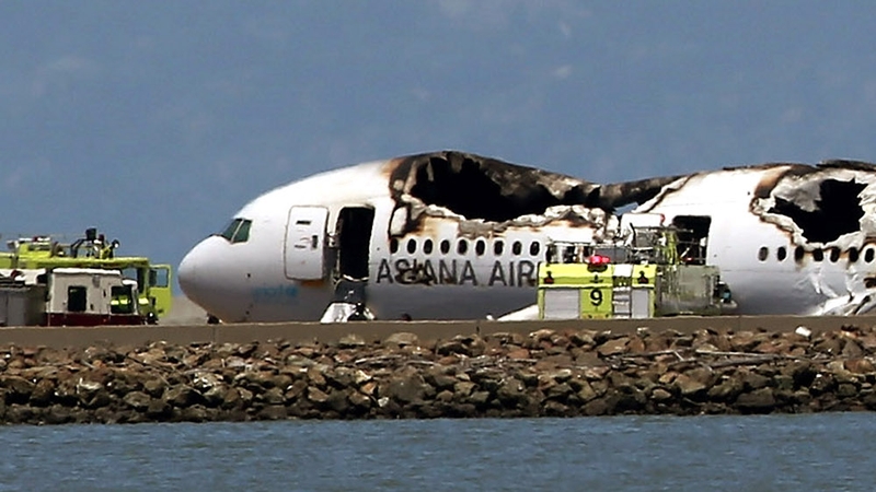 The Boeing 777 airplane lies burned near the runway after it crash-landed