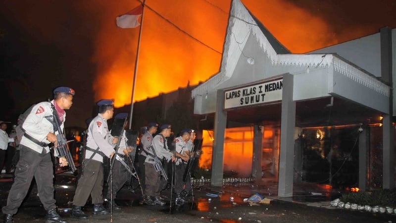 Armed Indonesian policemen secure the entrance of a compound at the prison in Medan