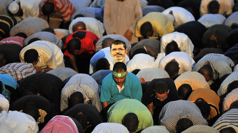 Supporters of Mr Mursi perform the evening prayer in Cairo last night