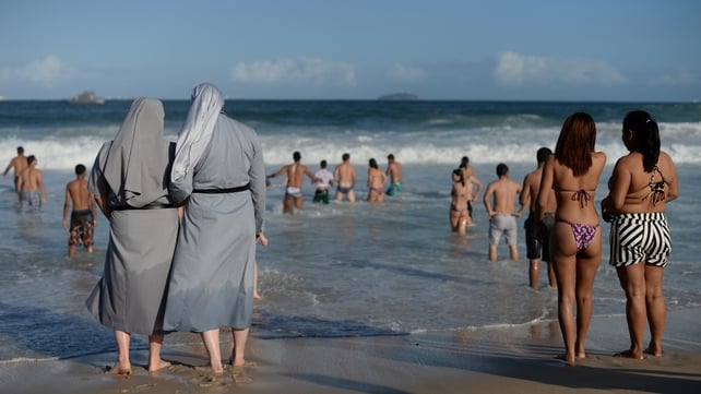 Two Polish nuns look on as youths enjoy the good weather