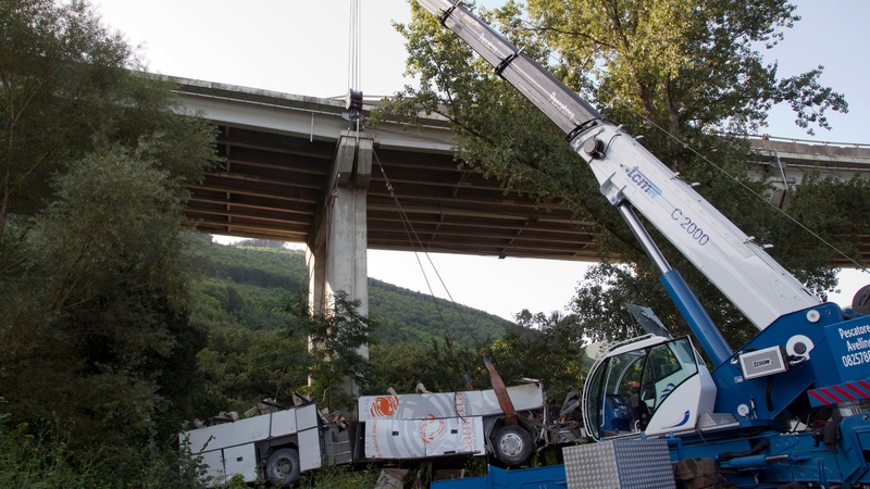 Workers remove the wreck of the bus from the scene