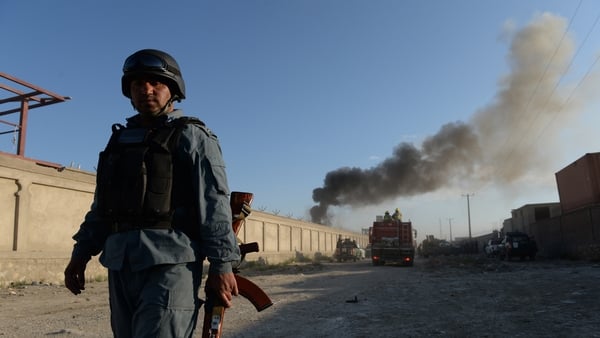 An Afghan policeman stands guard beside the site of a bomb attack in Kabul