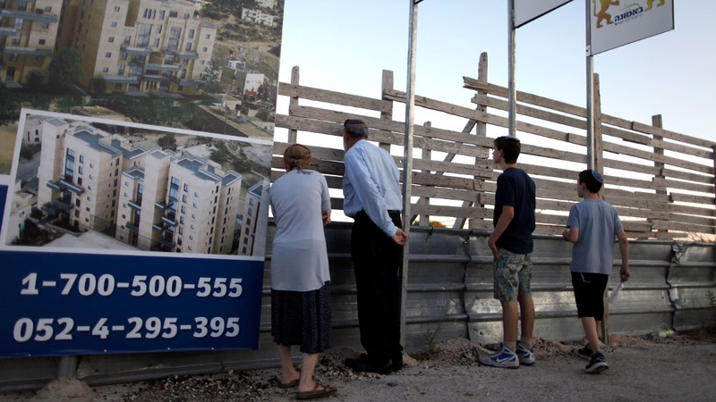 Israelis stand next to a sales promotion sign for a new Jewish neighbourhood in east Jerusalem