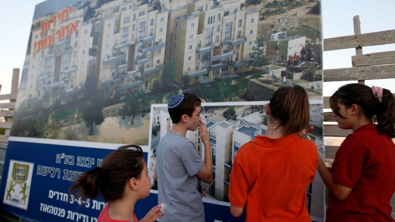 Israeli children stand next to a sales promotion sign for new Jewish neighbourhoods