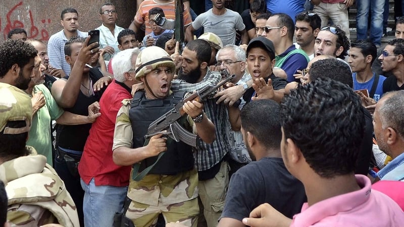 A soldier tries to control crowd while escorting a man out of Al-Fateh mosque in Cairo