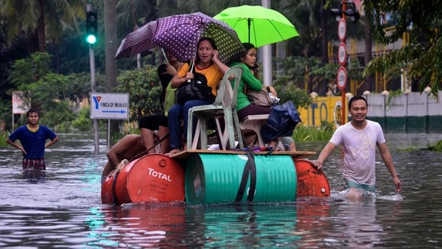People use a makeshift raft to make their way through the streets of Manila following flooding in the Philippine capital
