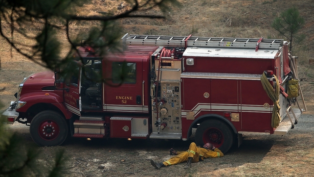 A fire fighter naps beside his truck in between shifts tackling the blaze