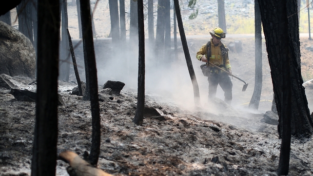 A fire fighter deals with any remaining 'hot spots' following the blaze