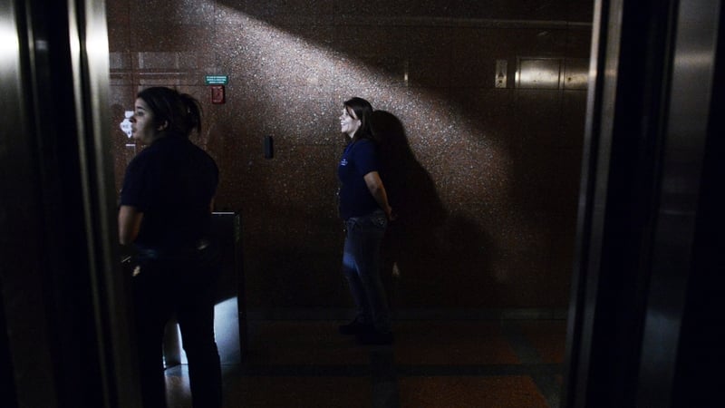 People stand in the corridor of a building during the blackout in Caracas