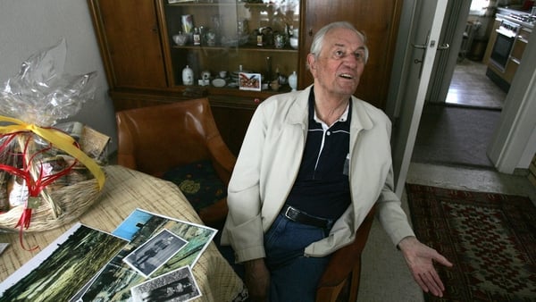 Rochus Misch sitting in his home in Berlin in 2005, with pictures of himself during the war