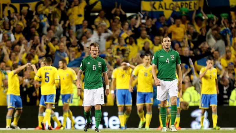 Glenn Whelan and John O'Shea dejected amongst a backdrop of Swedish celebration