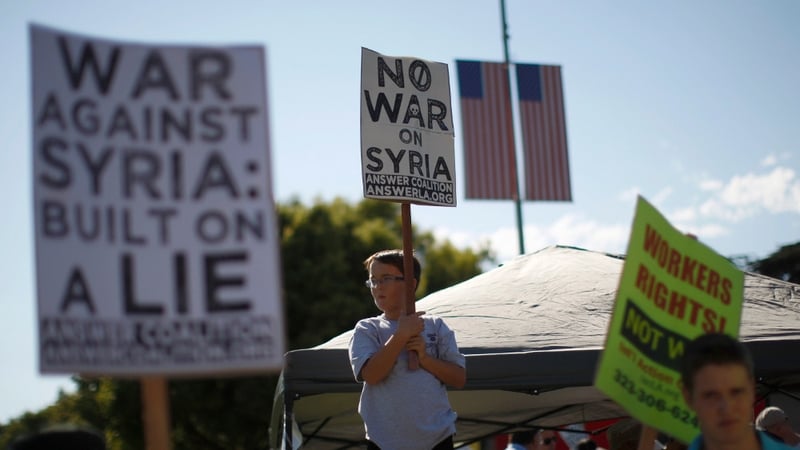 A boy holds a protest sign at a rally to urge Congress to vote against a limited military strike against the Syrian regime