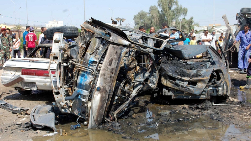 Iraqis gathering near burnt vehicles at the scene of a car bomb explosion in Nasiriyah, south of the Iraqi capital Baghdad