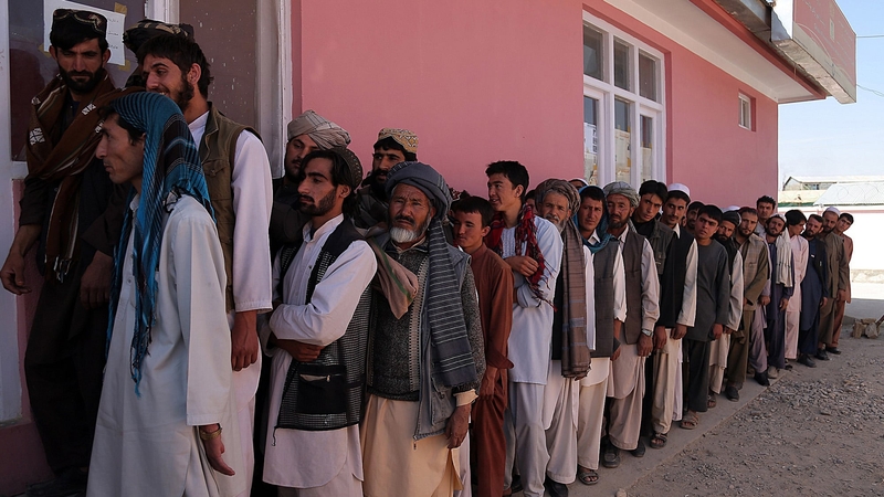 Afghan men wait to receive their identification cards to vote in upcoming elections at a registration centre in Ghazni