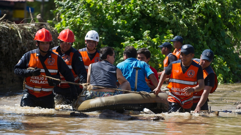 Rescued people are taken to safety by Mexican Federal Police officers on an inflatable dinghy in a flooded street of Acapulco