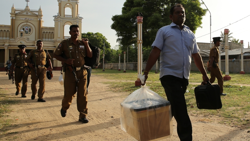 A Sri Lankan poll officer carries a sealed ballot box at a counting centre in Jaffna