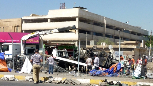 A destroyed vehicle is removed following a car bomb in a car park in Baghdad