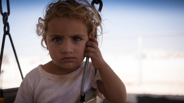 A young girl sits on a swing at the Zaatari camp