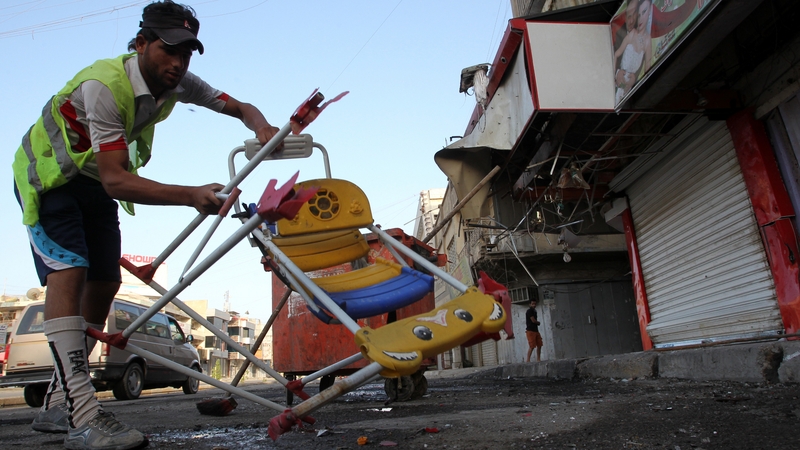 A worker clears up after a car bomb in Baghdad on a day in which at least 59 died in attacks
